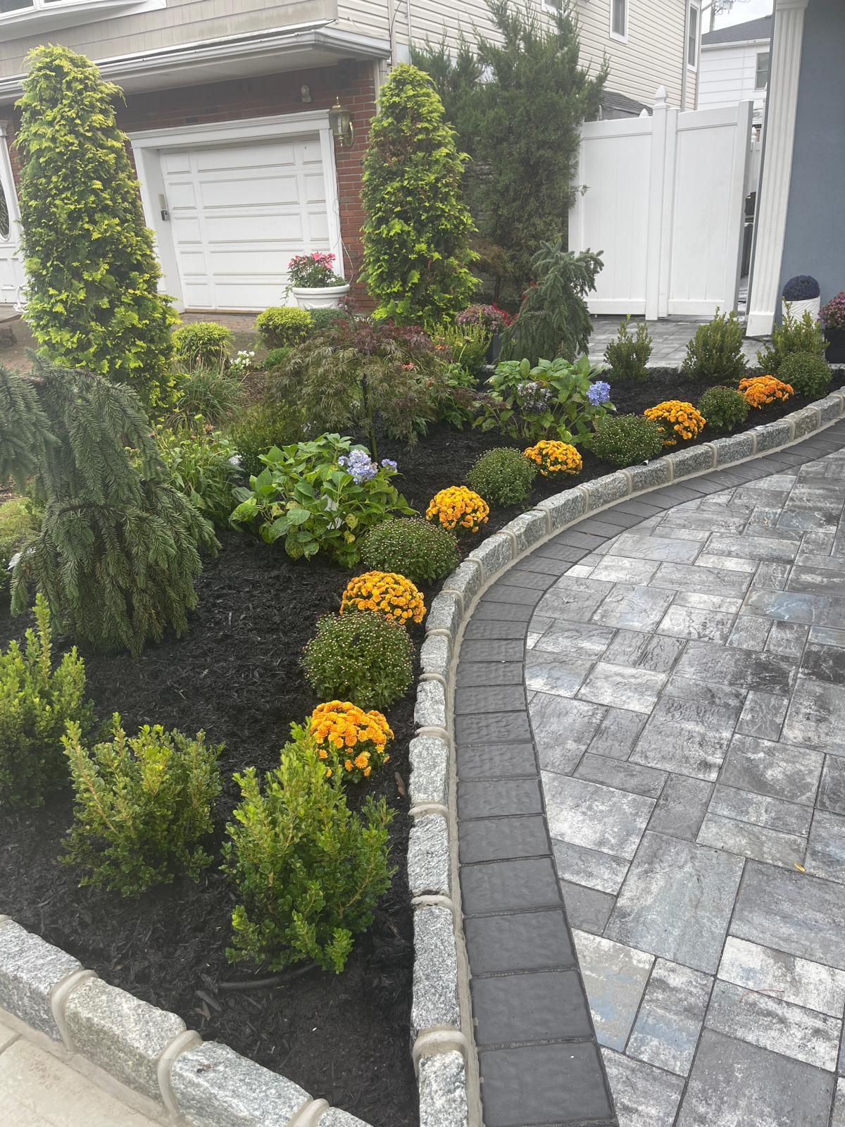 Curved paver border beside landscaped flowers